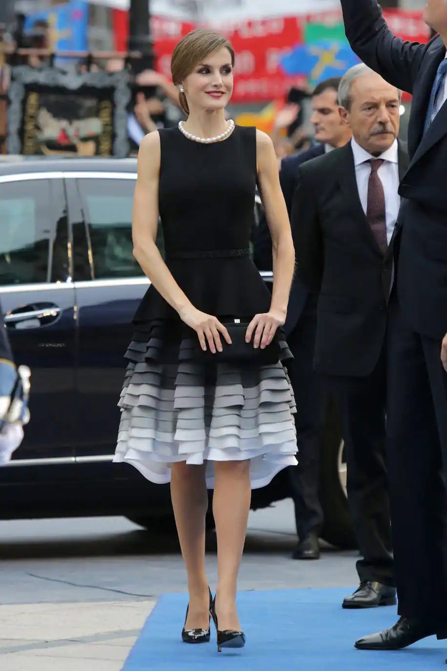 Uno de sus looks más comentados hasta la fecha. Para estos Premios Princesa de Asturias, Letizia eligió un vestido también de Felipe Varela en sisa con falda de volantes en negro, varios tonos grisáceos y blanco. Lo combinó con cluth y zapatos en negro y un elegante collar de perlas.