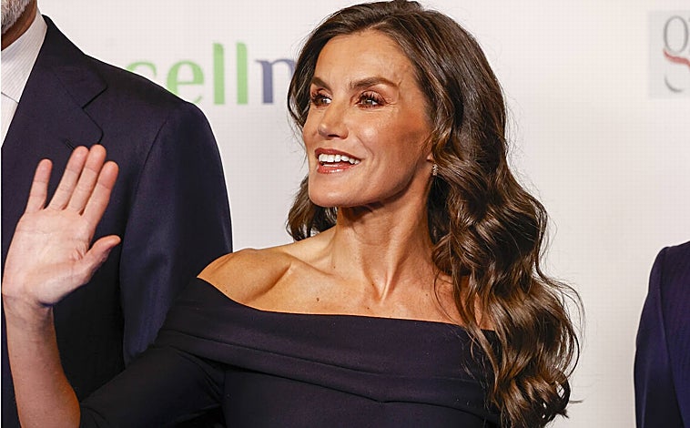 Imagen principal - La Monarca combinó un vestido negro con complementos metalizados y melena suelta rizada.