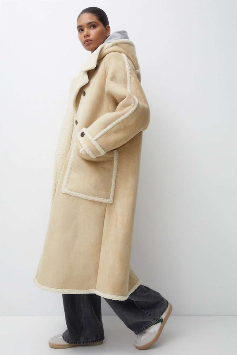 Pull & Bear. Abrigo largo de doble faz en tonos beige con forro de borrego. Precio: 69,99€.