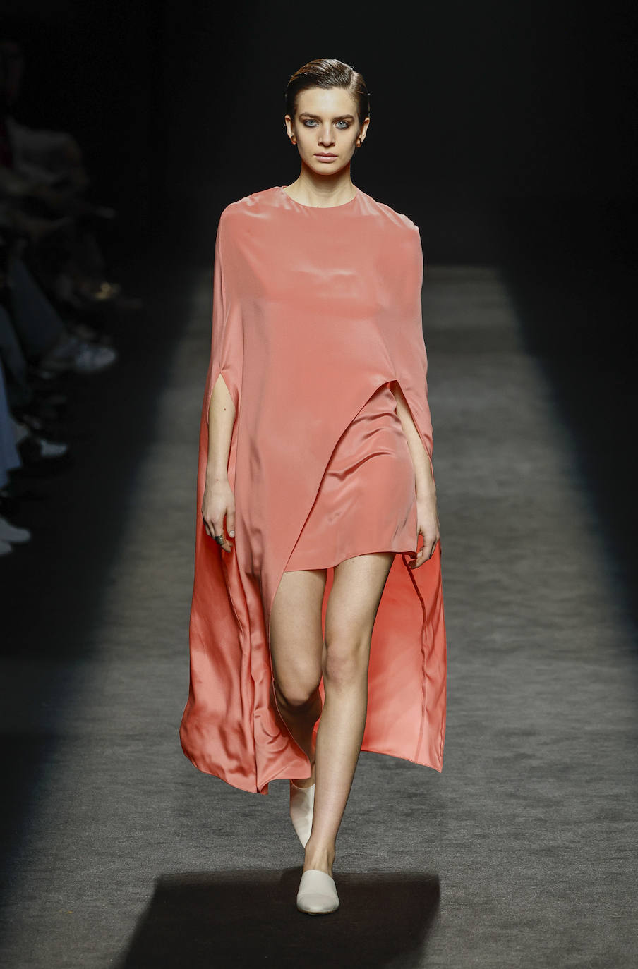 Minivestido con capa larga fluida en color coral, una de las propuestas más llamativas de la colección de Roberto Torretta. 