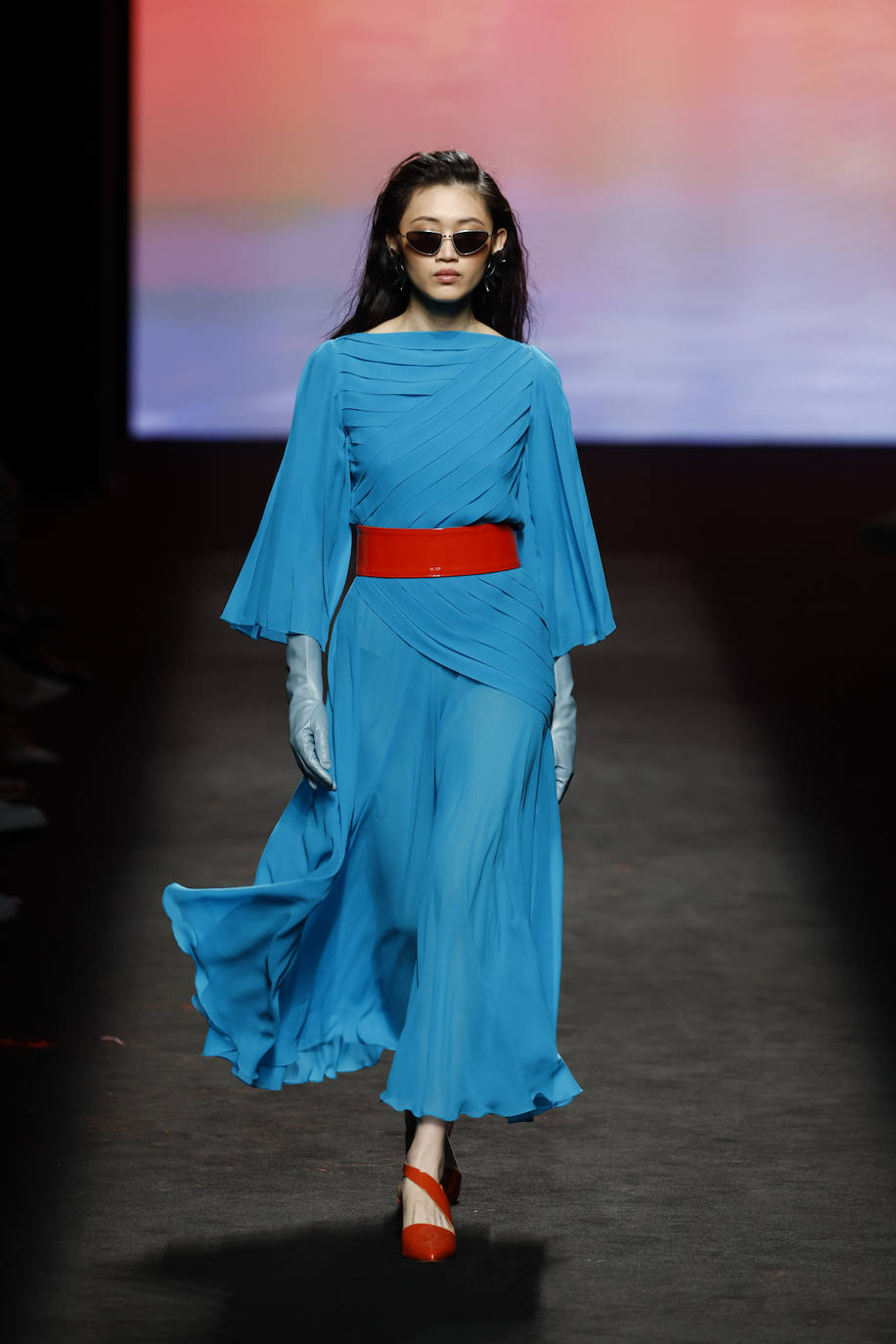 Los vestidos vaporosos de seda han sido otra de las propuestas de la diseñadora, como este modelo en un vigrante azul que combina con cinturón y zapatos en naranja. 