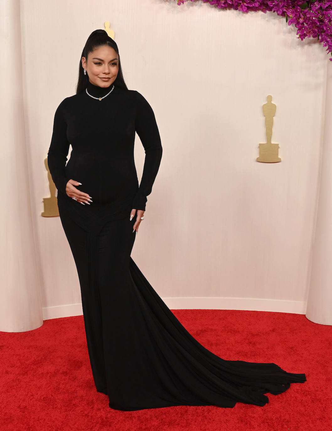 Una embarazada Vanessa Hudgens fue de las primeras en pasar por la alfombra roja de los Oscar 2024. Escogió un vestido negro de mangas largas, cuello alto y cola de Vera Wang.