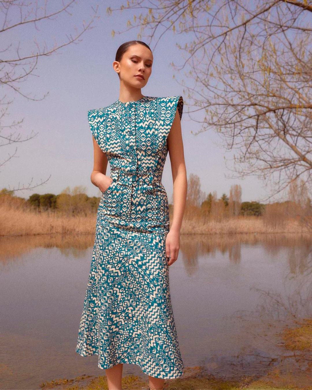 Vestido de corte midi con estampado geométrico en azul y blanco y detalle de solapas en la zona de los hombros. 185 euros en The IQ Collection.