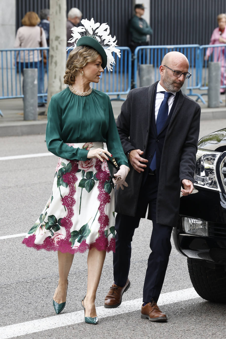 Almudena del Moral con conjunto de falda estampada y blusa verde y un llamativo tocado con plumas. 