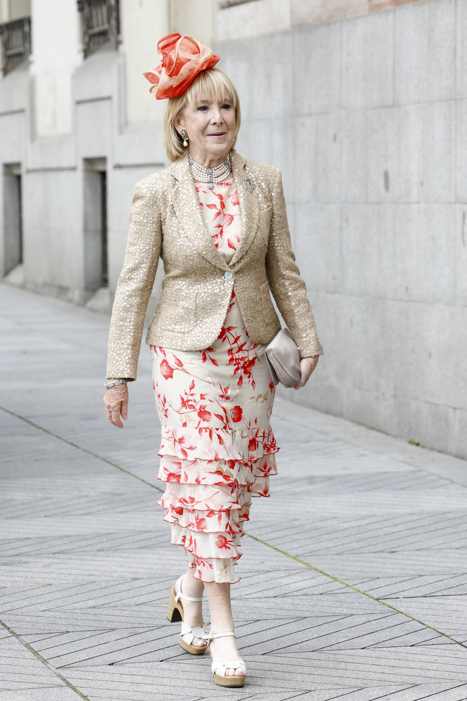 Esperanza Aguirre llegaba al enlace con vestido con bajo de volantes y estampado floral que ha completado con una blazer de tweed y un llamativo tocdo en tonos naranjas a juego con las flores del vestido. 