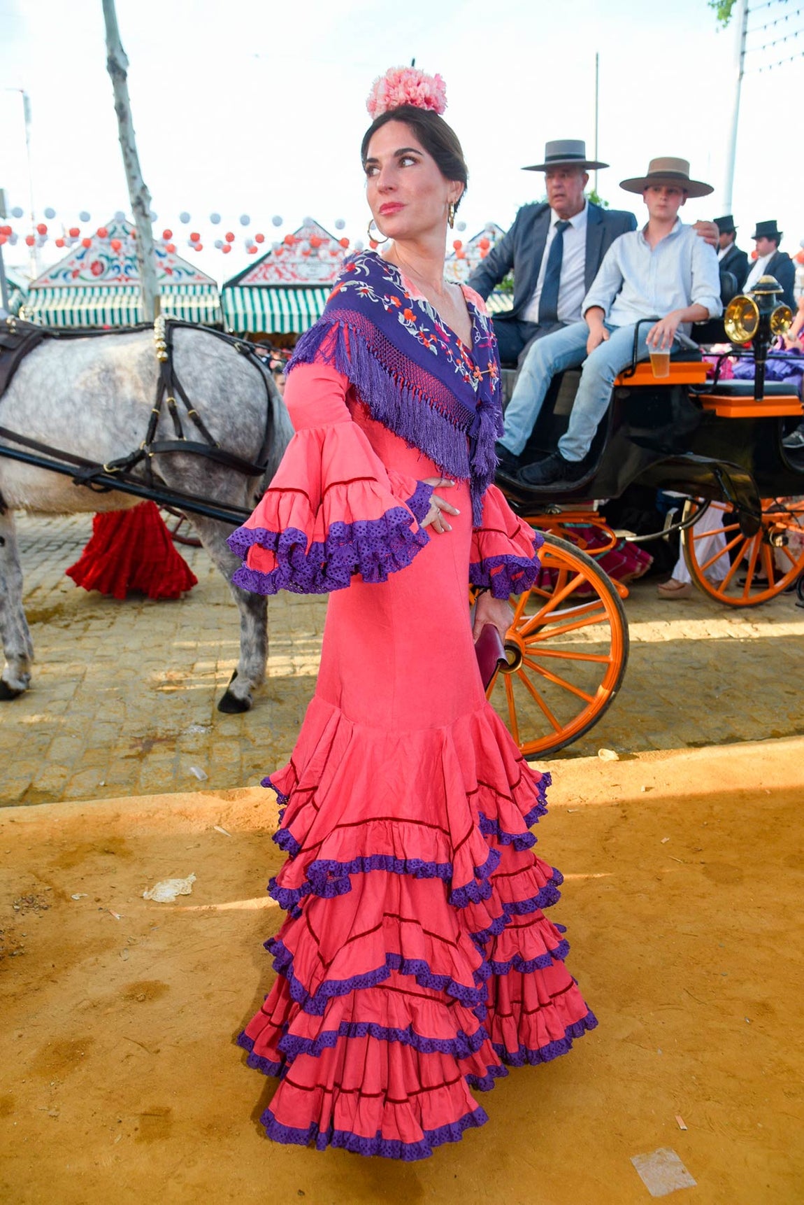 Lourdes Montes lució un vestido que combina tonos rojos y morados firmado por Miabril. Lo combinó con un mantoncillo y en el pelo lució dos flores de los mismos colores que el traje. 