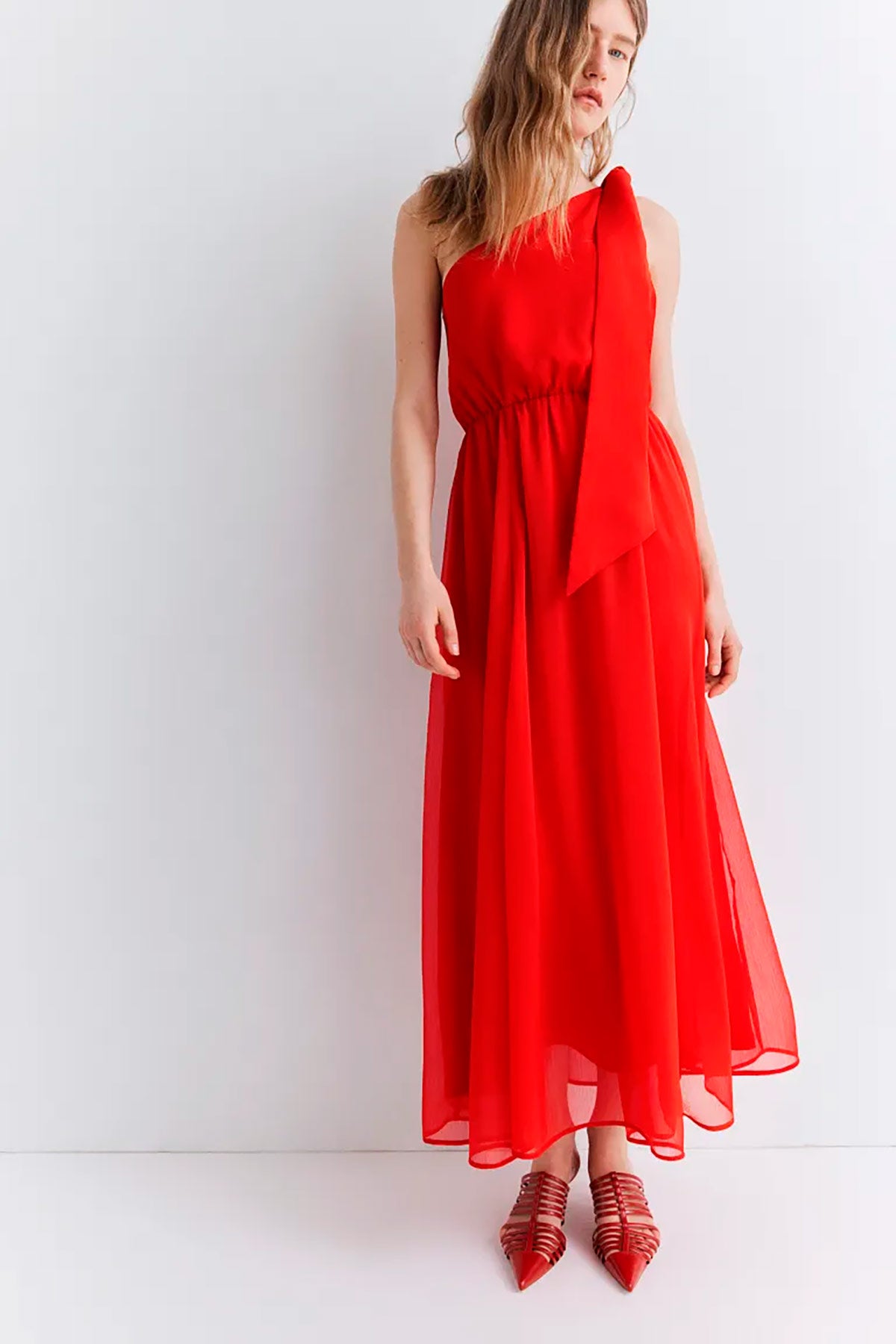 Vestido rojo de gasa con efecto arrugada y  escote asimétrico de un solo hombro decorado con un lazo. 44.99 euros en H&M.