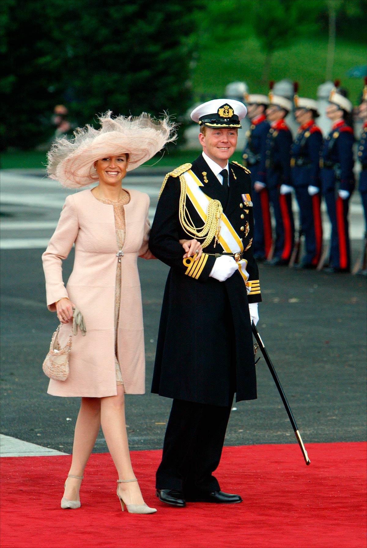 Máxima de Holanda, acompañada por su marido Guillermo, escogió un conjunto en color maquillaje compuesto por un abrigo y un vestido con bordado floral. En el pelo llevó una gran pamela de plumas a juego. 