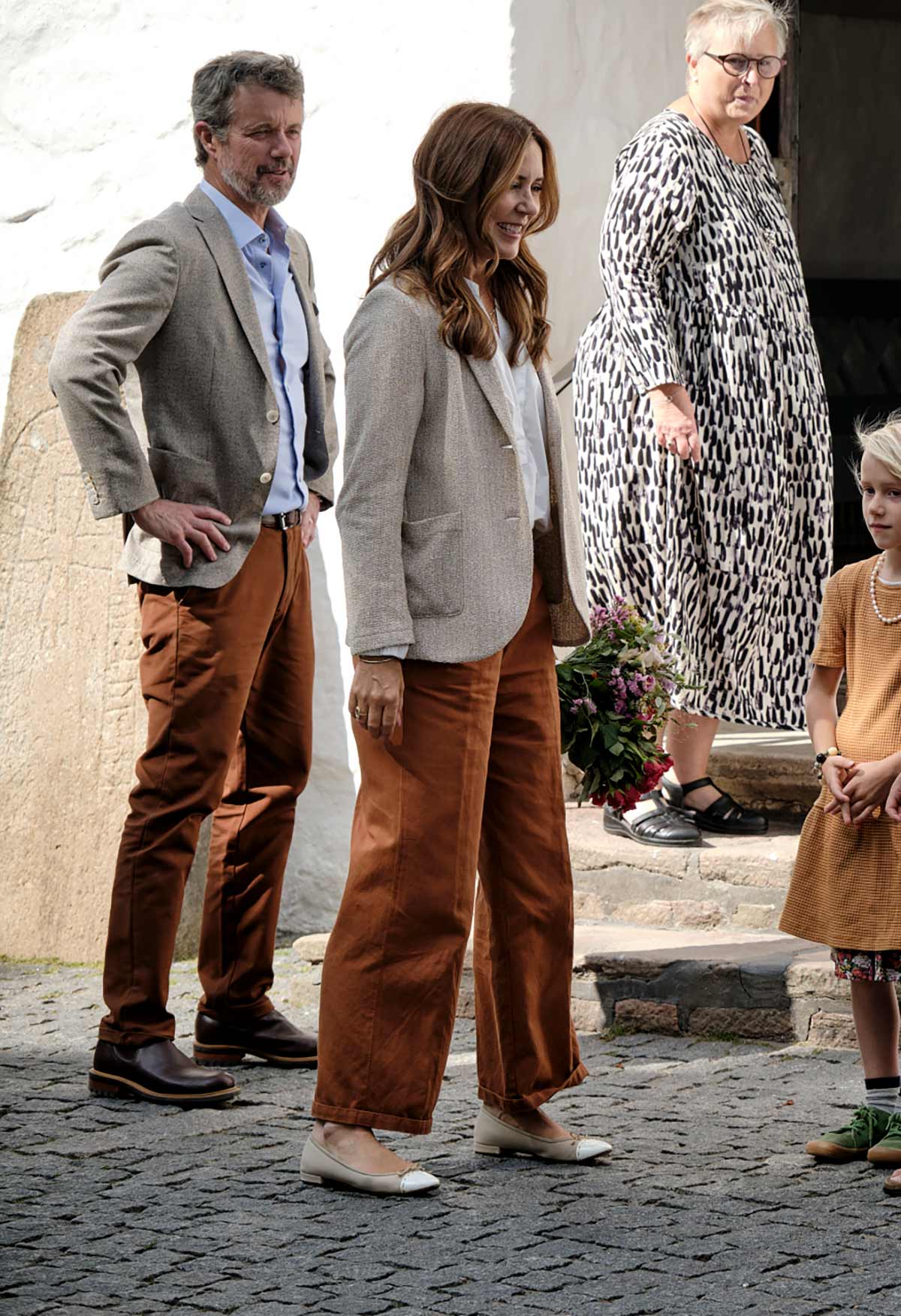 Perfectamente conjuntada, la reina consorte combinó unos pantalones largos en color teja con una camisa blanca y una blazer en beige de Harris Wharf London. En los pies, apostó por unas bailarinas con puntera en contraste firmadas por Prada. 