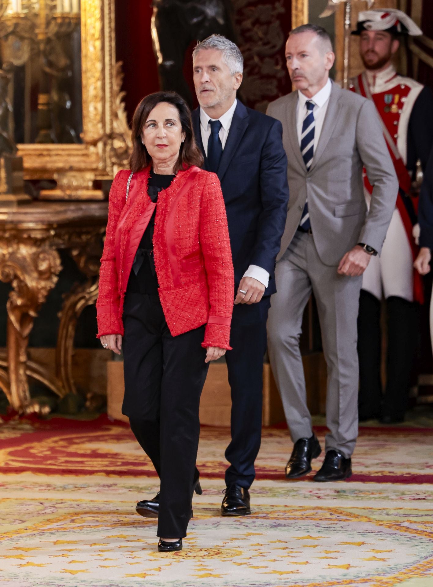 Con pantalón negro y chaqueta de tweed en color rojo, Margarita Robles llegaba a la recepción con los Reyes en el Palacio Real. 