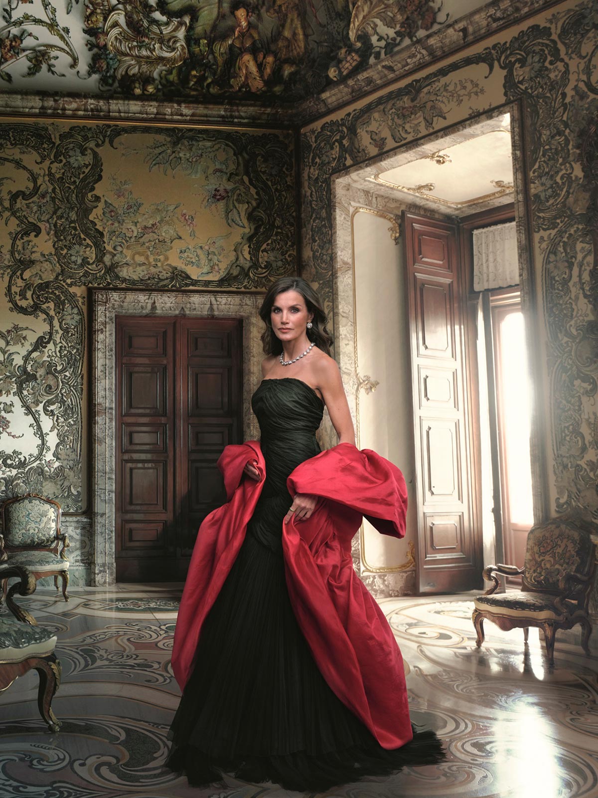 La Reina Letizia en el retrato de Annie Leibovitz. La monarca española, considerada una de las mujeres más elegantes del mundo, impresionó con un vestido de Balenciaga de 1948 cedido para la ocasión en color negro de tul y con escote palabra de honor que completó con una capa fucsia también de la misma marca. 