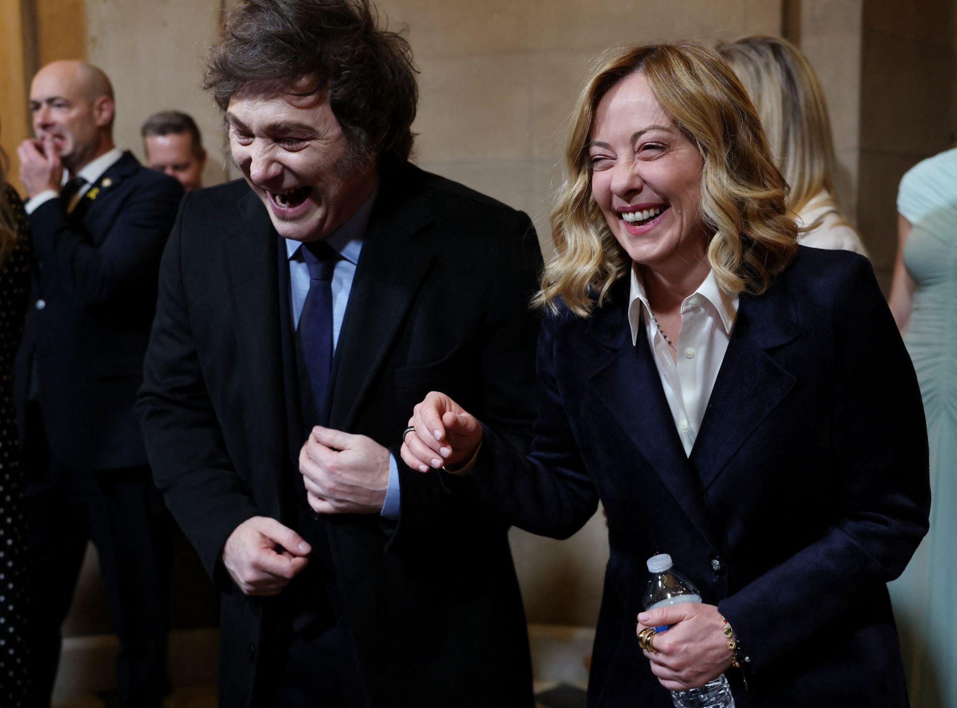 Giorgia Meloni con traje de chaqueta azul y camisa blanca junto a Javier Milei. 