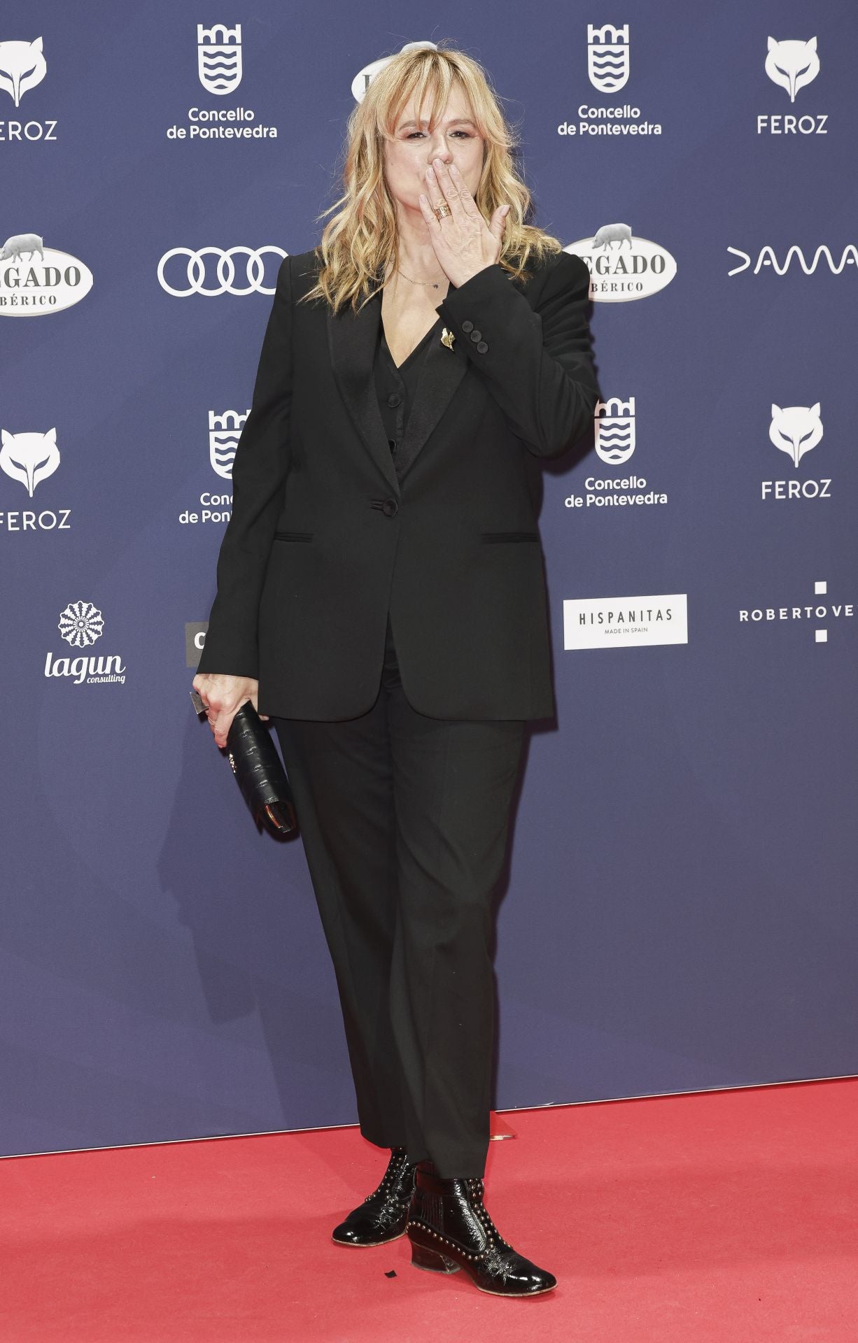 Emma Suárez, encargada de entregar el Feroz de Honor de esta edición a Jaime Chávarri, con esmoquin negro de Pedro del Hierro compuesto de americana con solapas de pico en satén, chaleco con ribetes en satén y pantalón recto.