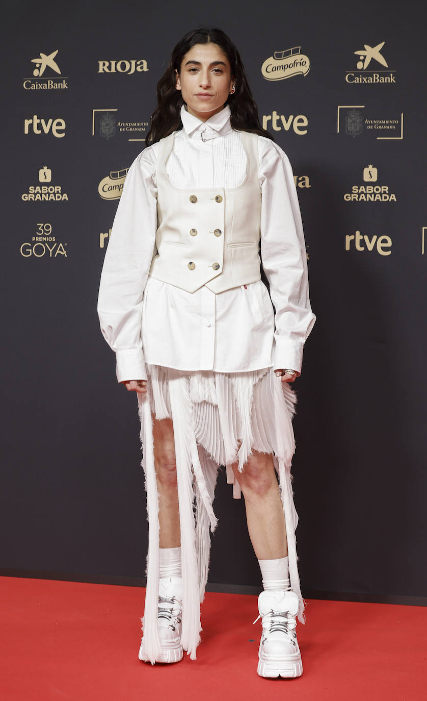 Carolina Yuste, nominada por su papel en 'La Infiltrada', eligió un curioso look en color blanco, formado por diversas piezas sobrepuestas (camisa, chaleco, falda) que completó con zapatillas deportivas. 