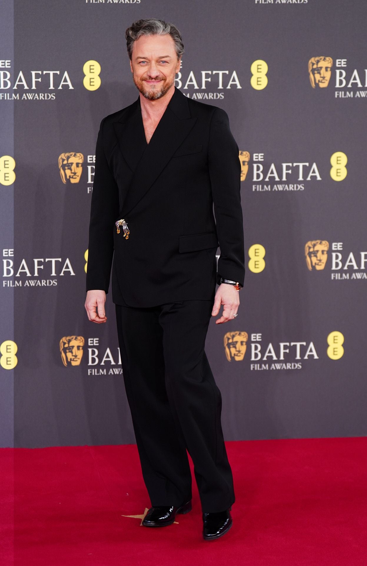 James MacAvoy eligió un estilismo en negro con chaqueta cruzada que adornó con un llamativo broche. Además, lució el reloj de lujo IWC Portugieser Perpetual Calendar 44 con esfera Obsidian y caja de 18 ct Oro Armor.