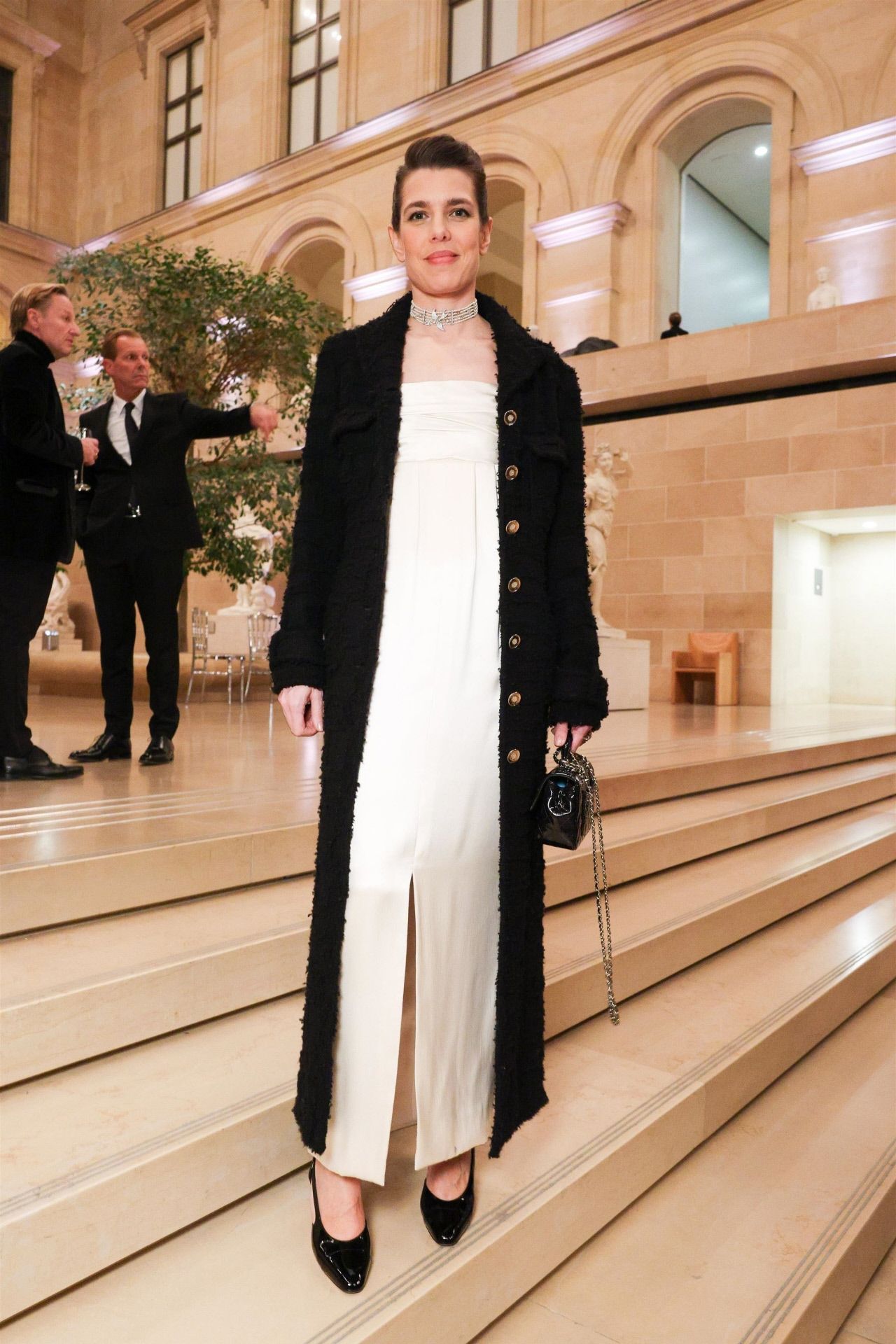 Carlota Casiraghi eligió un vestido blanco con abertura central y abrigo de tweed largo en color negro de Chnael. Lo combinó con salones negros y bolso de la Maison. 