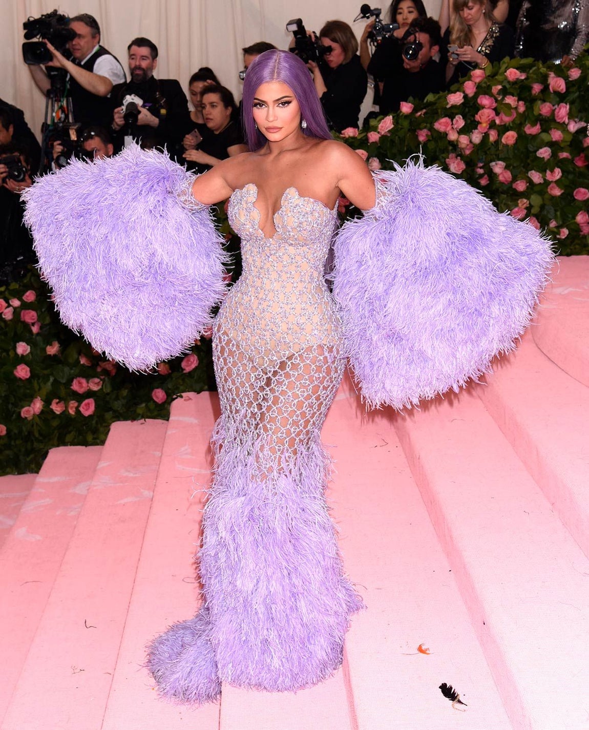 Kylie Jenner se vistió de sirena en la Gala Met de 2019 con un vestido morado semitransparente de rejilla con un body y escote palabra de honor. El bajo estaba repleto de plumas al igual que los manguitos. Era obra de Versace