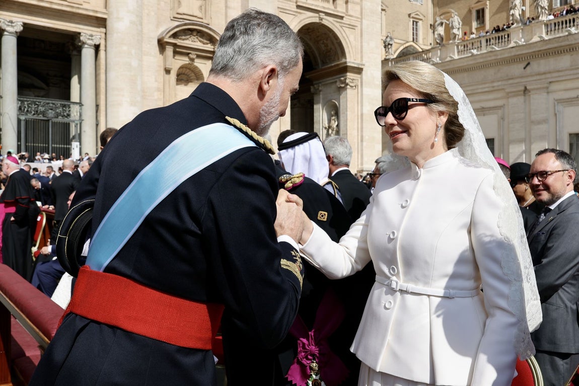 Matilde de Bélgica llevó un dos piezas en blanco, formado por una falda midi con vuelo y blazer cerrada con cinturón de Dior. Lo combinó con un bolso mini y salones blancos, también de Dior, mantilla en la cabeza, y gafas de sol de Gucci.
