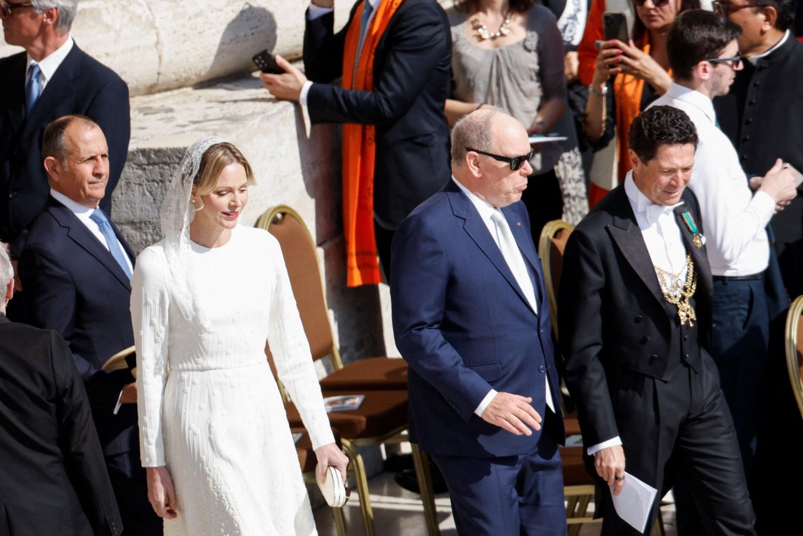 Charlene de Mónaco eligió un vestido blanco midi, de manga larga y escote redondo, confeccionado con tela con relieve de la firma de alta costura Elie Saab. Lo combinó con salones altos, bolso de mano y mantilla de encaje, todo en blanco.