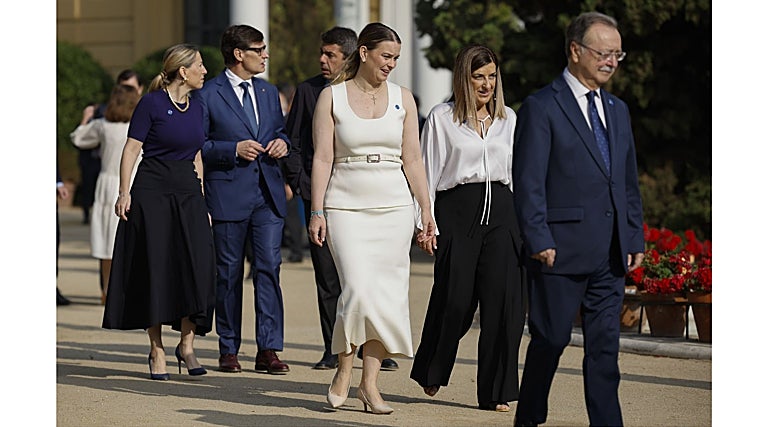 Marga Proens, que debería de cambiar el top de tirantes por una blusa blanca globo, pasea junto a María Guardiola, que viste acorde con el acto y las tendencias de moda