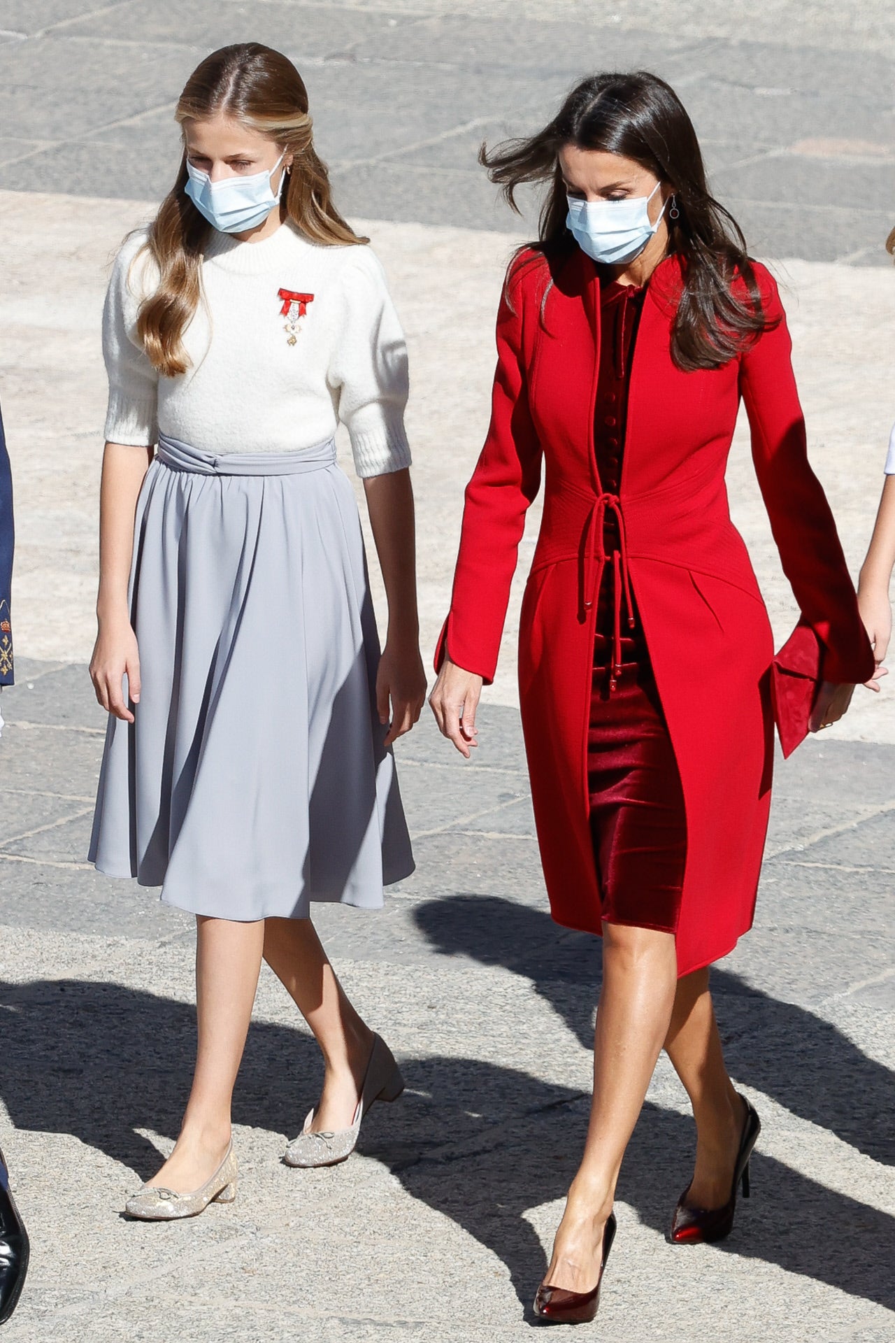 2020 fue el año marcado por la pandemia de la COVID-19. Para la celebración del 12 de octubre, la Reina Letizia se decantó por un vestido de terciopelo rojo de corte midi con una chaqueta de cuello mao y una doble lazada de cierre. Lo conjuntó con unos salones en tono cereza y un bolso de mano del mismo color.