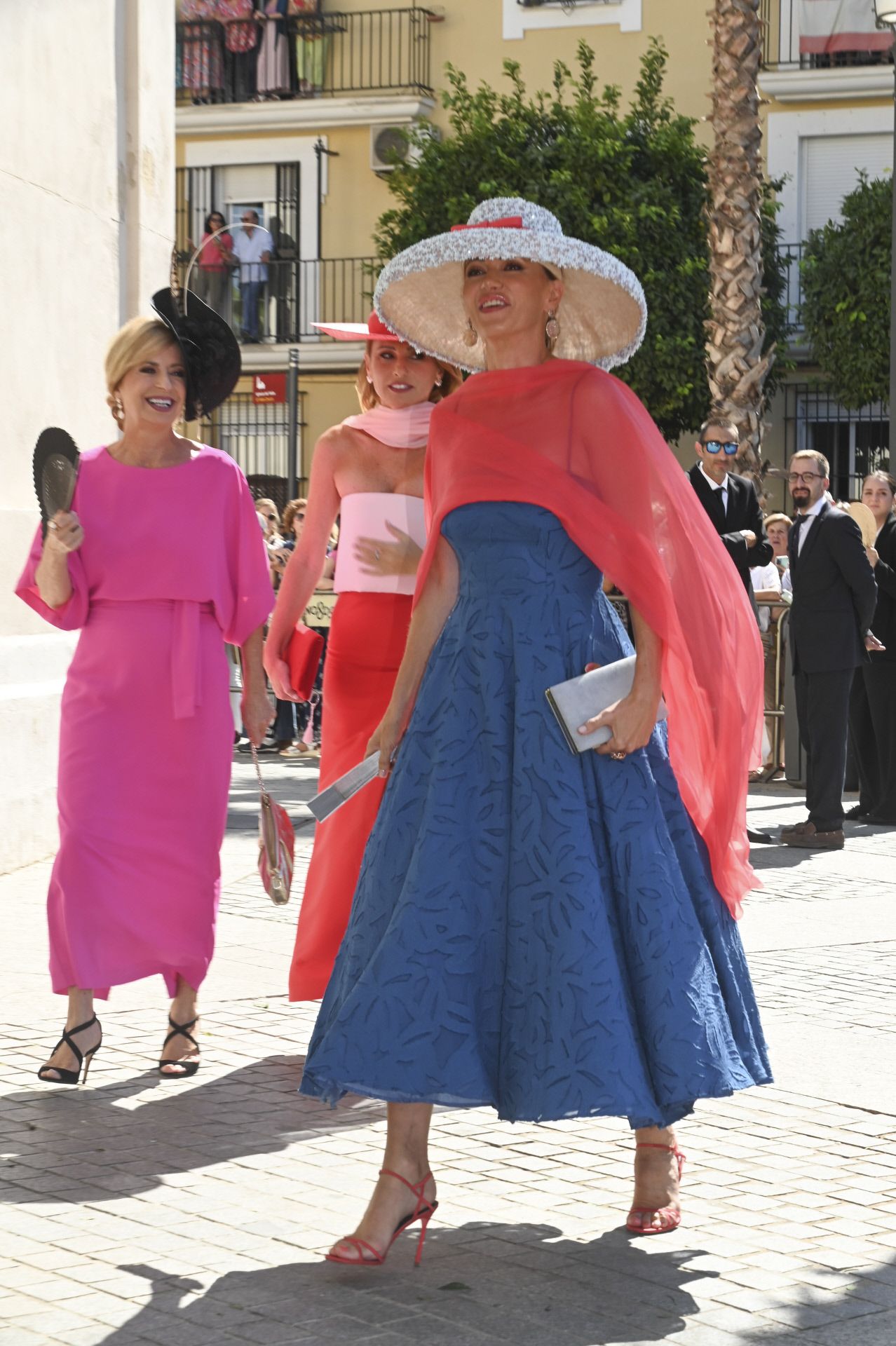 Susanna Griso eligió un vestido de Redondo Brand en color azul, con tirantes y falda evasé, que combinó con un chal de gasa en tono coral y una gran pamela de Balel. La presentadora recogió su melena en un moño de bailarina, y lució sandalias de tacón alto, a juego con el chal. Además, completó el estilismo con pendientes y anillo de San Eduardo Jewels.