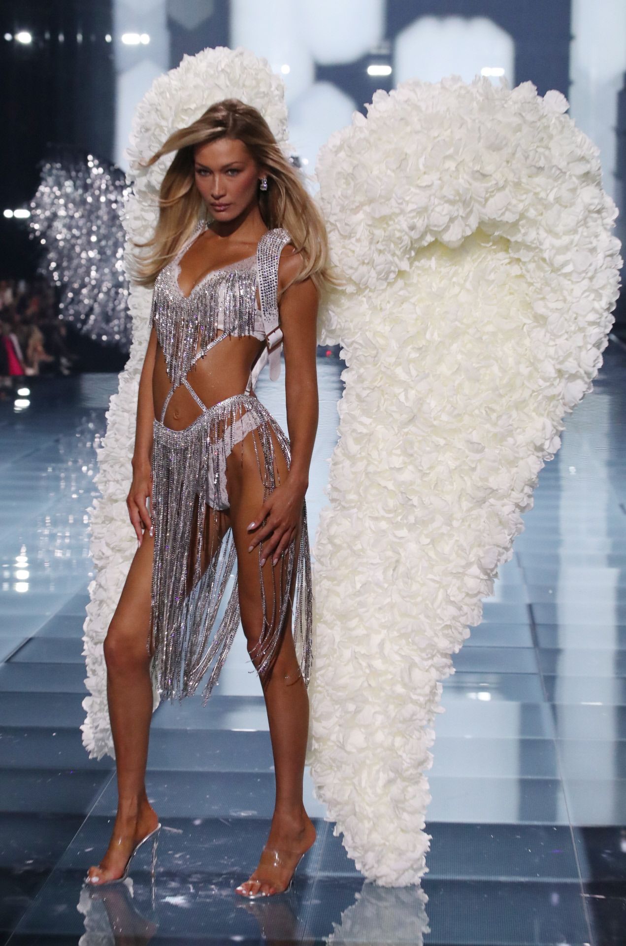 Bella Hadid con alas blancas y un conjunto en blanco con flecos metalizados. 