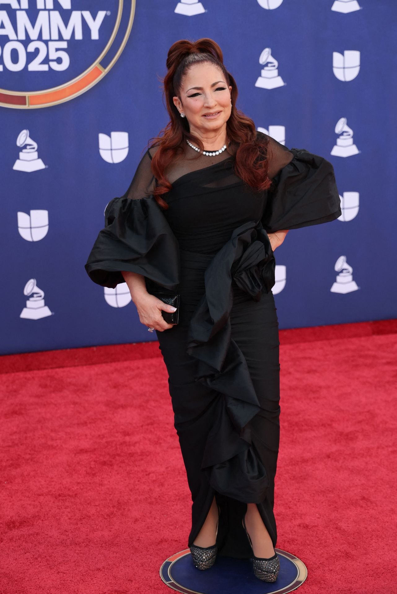 Gloria Estefan también eligió el color negro y lució un vestido  con mangas farol y volante central que recorría el diseño desde la cintura. 