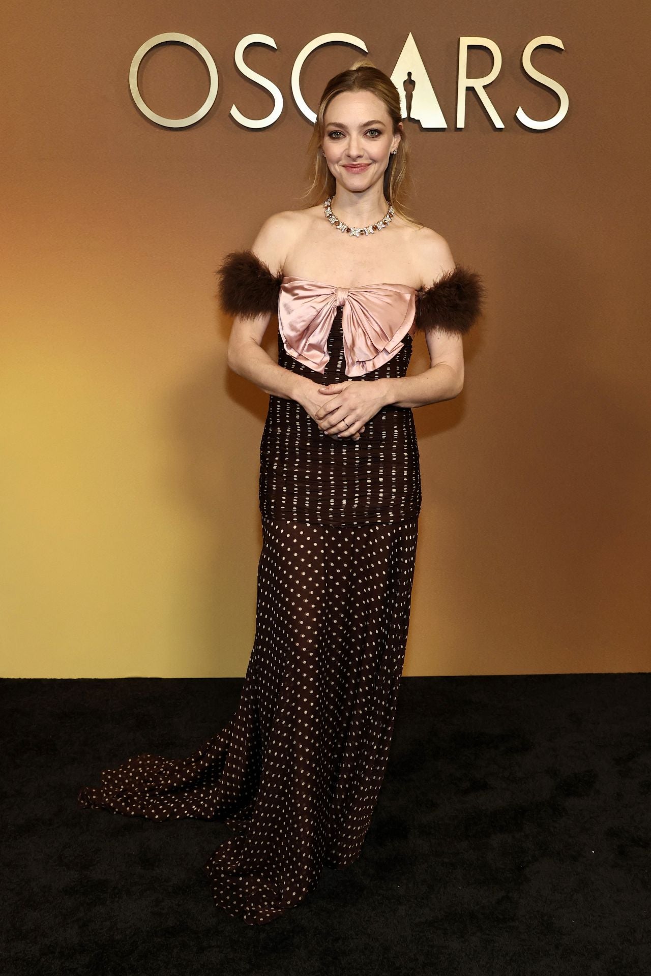 Amanda Seyfried optó por un diseño de Valentino, de la colección Resort 2026. Un vestido con cuerpo de lunares con un lazo rosa en el pecho y originales tirantes de marabú. 