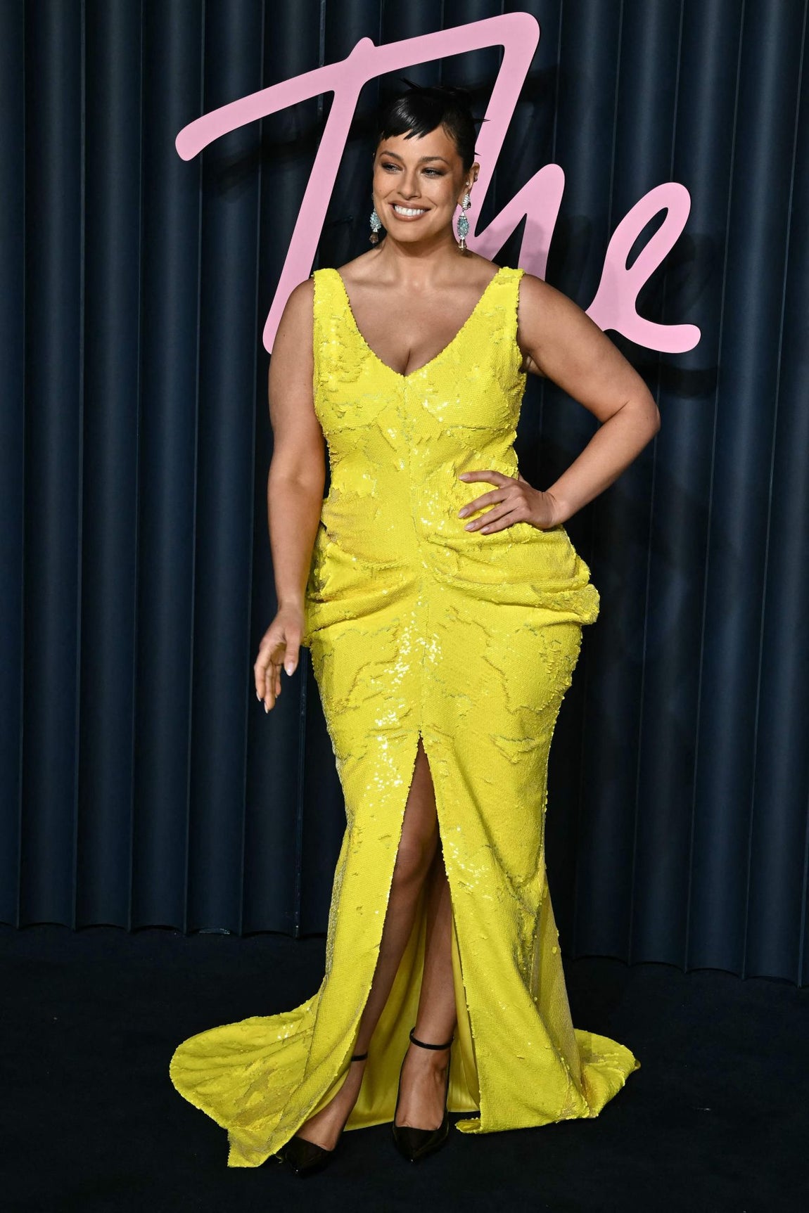 Ahsley Graham eligió un llamativo vestido en color amarillo con escote en V y abertura central, cuajado de lentejuelas y con fruncidos a la altura de las caderas. Lo combinó con salones con pulsera. 