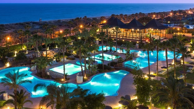 Vista nocturna de los jardines y piscinas de este hotel situado en primera línea de playa