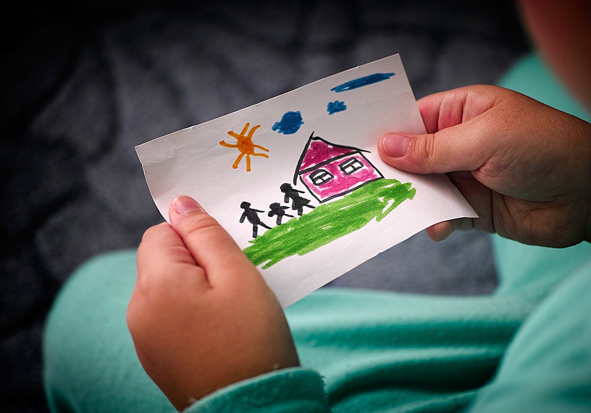 Un niño sostiene un dibujo de una familia