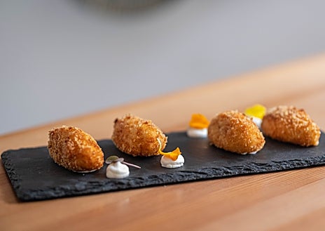 Imagen secundaria 1 - Arriba, barra alta de Killo con vistas a la cocina. Abajo, sus croquetas de coliflor y la carrillada de vaca vieja con crema y crujiente de chirivía