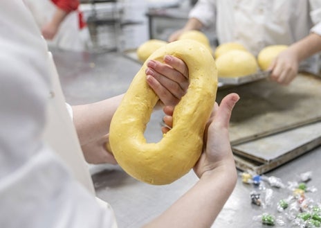 Imagen secundaria 1 - Sobre estas líneas, arriba, roscón clásico relleno de nata de La Mallorquina. Abajo, a la izquierda, formado de roscones en el obrador de Mallorca. A la derecha, roscón de Umikobake