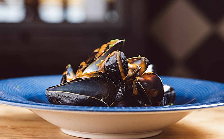 Imagen principal - Sobre estas líneas, algunos de los platos de Moments. Las conchas abiertas en el josper son una de sus especialidades. Arriba, los mejillones 'cabreaos'. Abajo a la derecha, los berberechos. Al lado, una de la decena de cocas que ofrecen