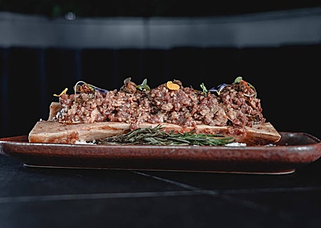 Imagen secundaria 1 - Varios platos de Showroom. En la foto general, el steak tartar sobre tuétano, la quinta costilla de vaca finlandesa al teriyaki y la torrija. Abajo, de nuevo el steak tartar y el carpaccio.