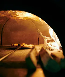 Imagen secundaria 2 - Sobre estas líneas, el local de Sartoria Panatieri en Eixample. Abajo, a la izquierda algunos de los platos que acompañan su oferta de pizzas. A la derecha, su horno de leña