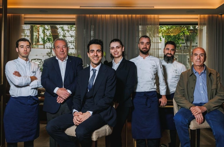 Carmelo Pérez (segundo por la izquierda) y Esteban Sánchez-Torres (primero por la derecha) posan junto al equipo de Saddle, el estrella Michelin que ocupa hoy el local del extinto restaurante Jockey que diseñó y sirvió el menú de la boda real de Don Felipe y Doña Letizia el 22 de mayo de 2004. De izquierda a derecha, Alberto Barba –jefe de cocina–; Carmelo Pérez; Israel Ramírez –director de Saddle–; Yuri Montoya –jefa de sala–; Pablo Laya –chef–; Noam González –jefe de cocina–; y Esteban Sánchez-Torres