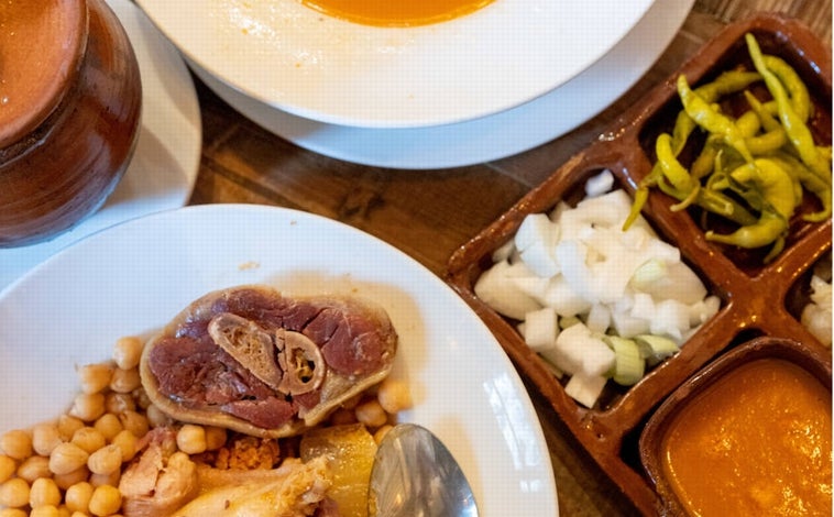 Imagen principal - El cocido, la pizza de ropa vieja y los buñuelos de manzana de La Rayúa, en Madrid.