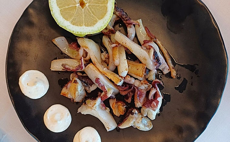 Imagen principal - Sobre estas líneas, uno de los fueras de carta que Cata tiene este verano: sepia sucia a la plancha; Abajo, a la izquierda, boquerones a la bilbaina. A la izquieda, sus croquetas de cocido y jamón