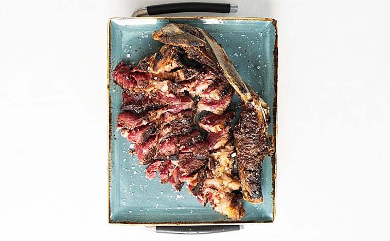 Imagen principal - Sobre estas líneas, la célebre chuleta de Askua. Abajo, dos de los fuera de carta con los que el chef David Vázquez quiere ampliar el horizonte culinario de su restaurante. Unos tomates sobre una emulsión de escabeche de pollo y unos sepionets con consomé oscuro y trufa de verano