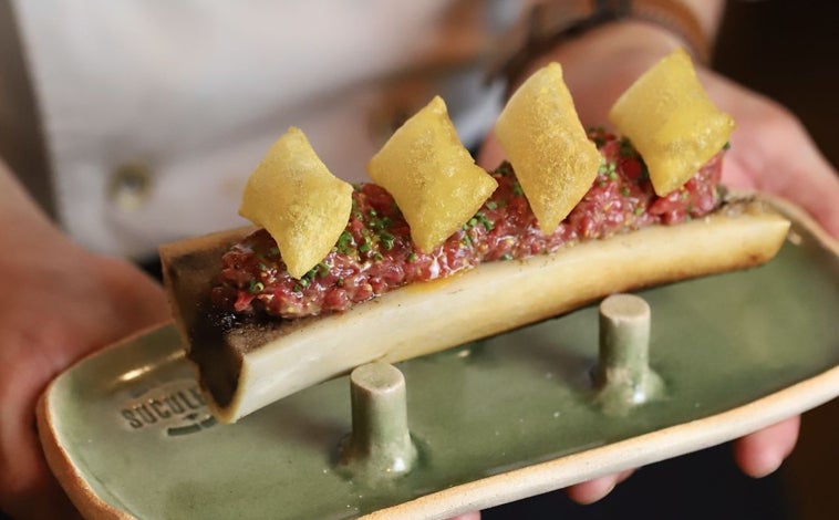 Imagen principal - Sobre estas líneas, arriba, el steak tartar tibio sobre medio hueso de caña con su tuétano y patatas soufflé. Debajo, a la izquierda, la croqueta de pato, todo un icono en Barcelona. Al lado las colmenillas rellenas de foie de Toni Romero