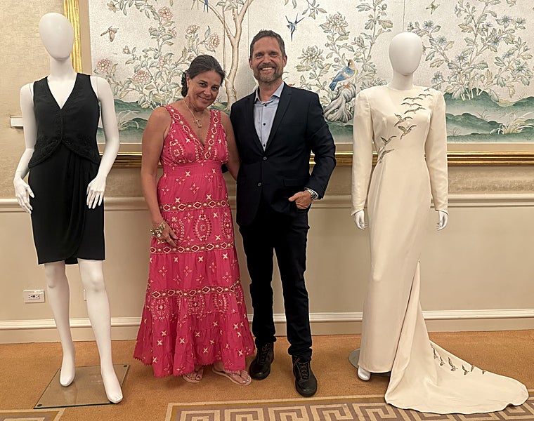 Renae Plant y Livinio Stuyck con dos de los vestidos de la subasta