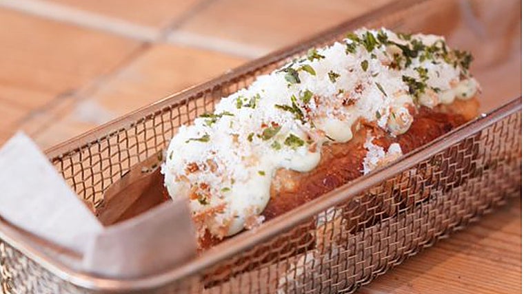 Perrito de gambones con salsa de mostaza, miel, eneldo y queso parmesano.