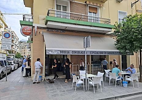 Imagen secundaria 1 - Curro, detrás de la barra en la que ha estado 63 años; abajo, la fachada de la Bodega Consolación antes de cambiar de manos; y a la derecha, el cartel del homenaje que se le ha preparado este lunes en la Bodega Consola