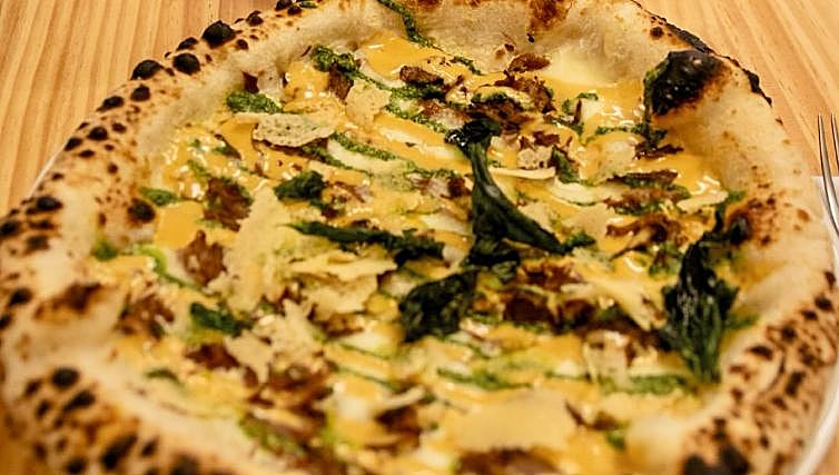 Pizza de carrillada de Berrinche 'amasa la fiera' candidata a mejor pizza de España, con base blanca, carrillada ibérica estofada, pesto de albahaca, lascas de parmesano y un jugo de carrillada reducido
