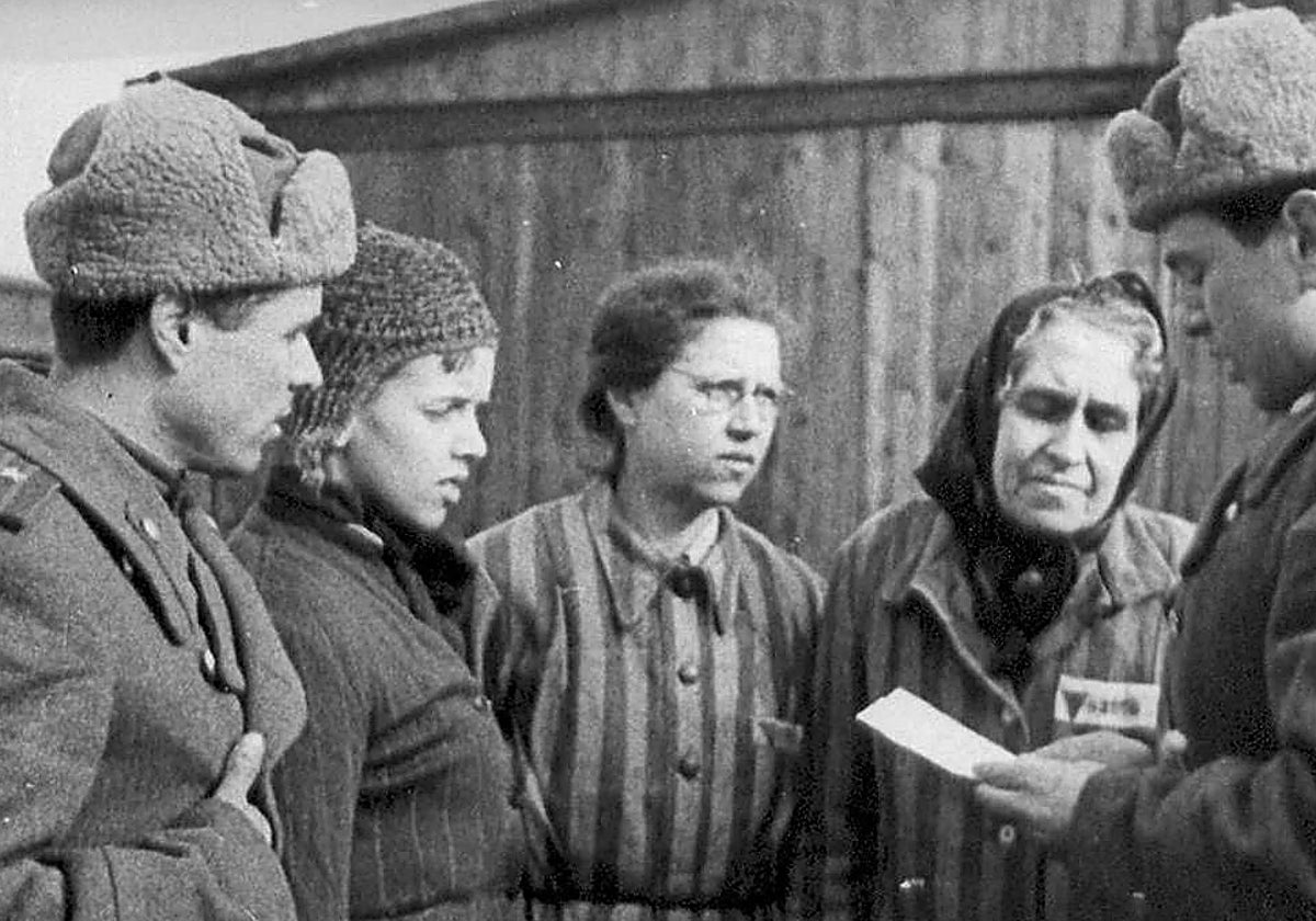 Varios prisioneros de Auschwitz hablan con un soldado en el momento de la liberación del campo de concentración