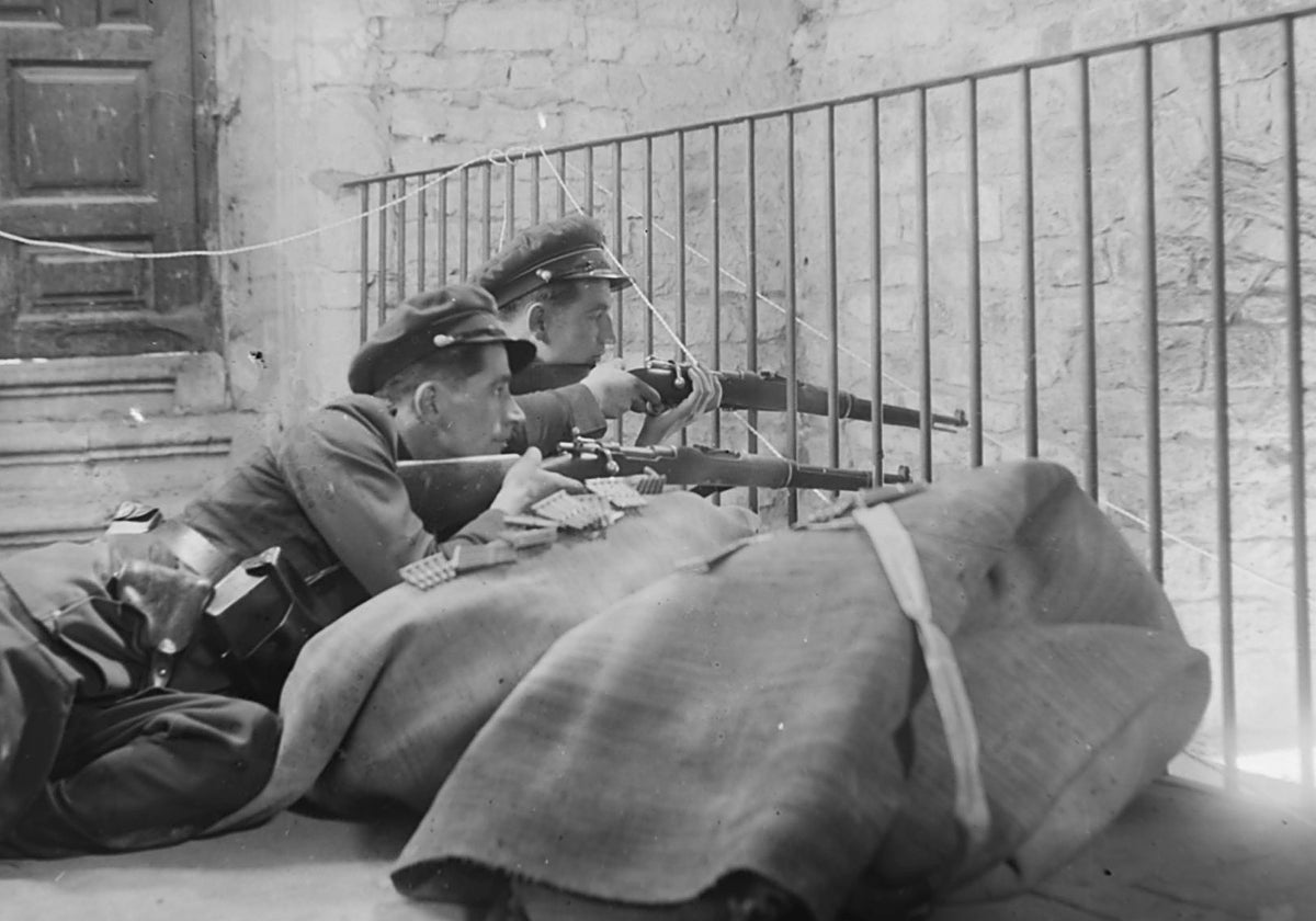 Dos guardias de asalto, apoyados sobre unas alfombras, defienden la Catedral de Oviedo, cuya Cámara Santa fue dinamitada, durante los sucesos de la Revolución de Asturias