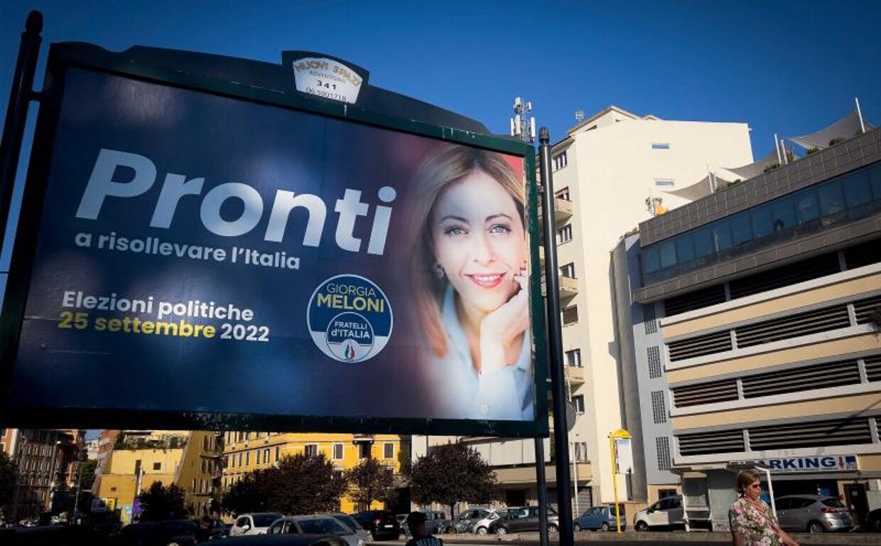 Los peatones pasan frente a un cartel electoral de Giorgia Meloni, líder de extrema derecha del partido Fratelli D'Italia 'Hermanos de Italia' que se exhibe en Roma