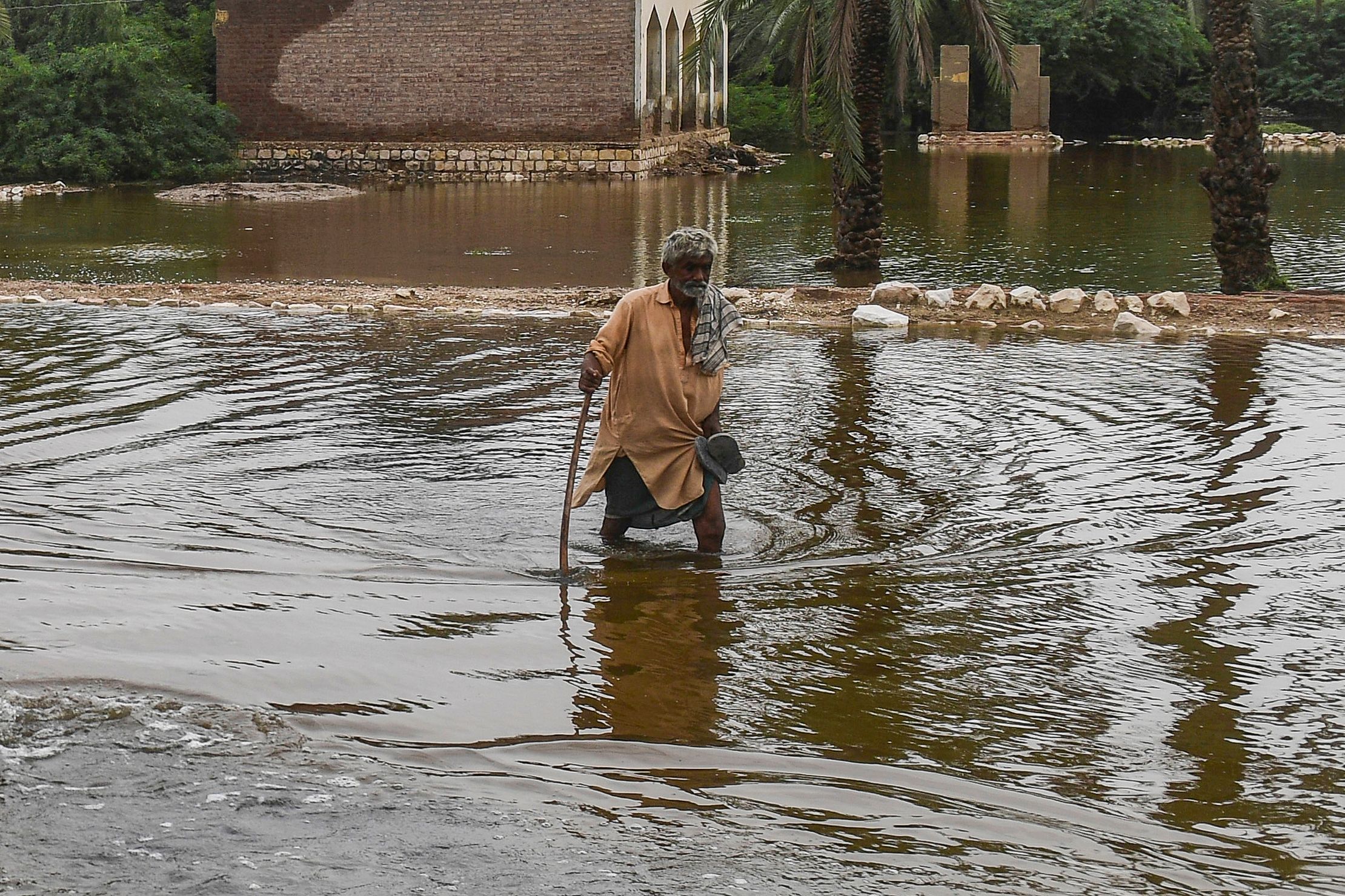 Un hombre camina a través del agua acumulada en las calles de su ciudad.
